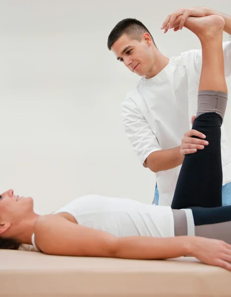 Physiotherapeut streckt Bein des Athleten — Stockfoto