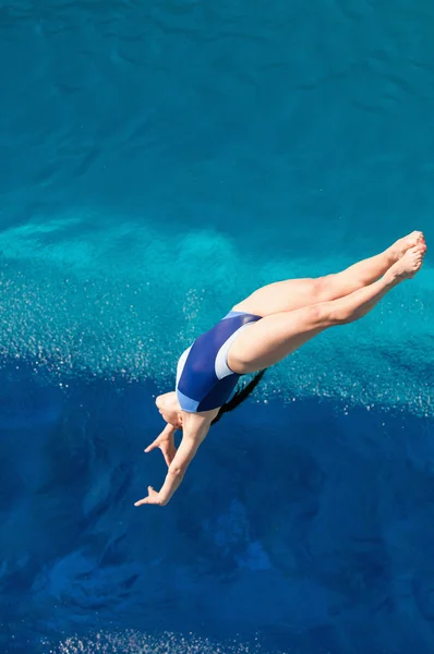 Femme dans l'air pendant la plongée arrière du tremplin — Photo