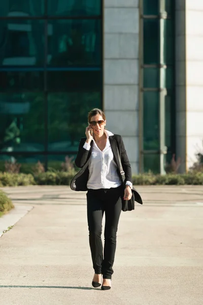 Affärskvinna promenader och med mobiltelefon — Stockfoto