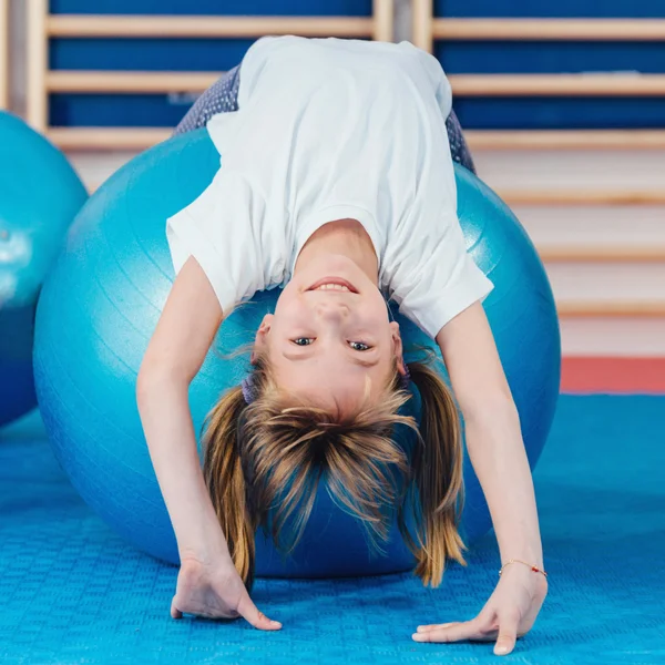 Kleines Mädchen streckt sich über Fitnessball — Stockfoto