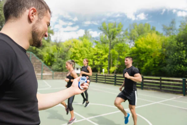 Entrenador con cronómetro durante el entrenamiento cardiovascular — Foto de Stock