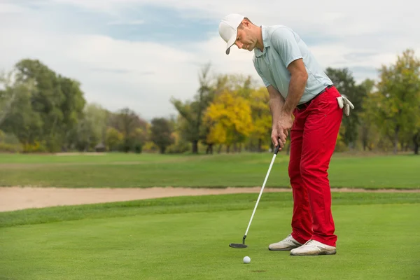 Golfista poniendo pelota en el agujero — Foto de Stock