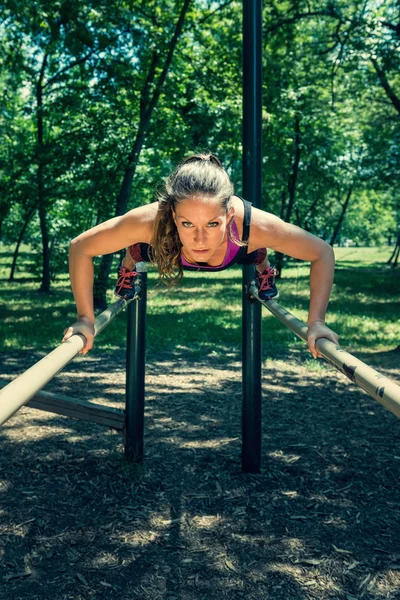 Athlete doing push-ups on bars — Stock Photo, Image