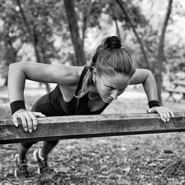 Athlete doing push ups at trail barrier — Stock Photo, Image