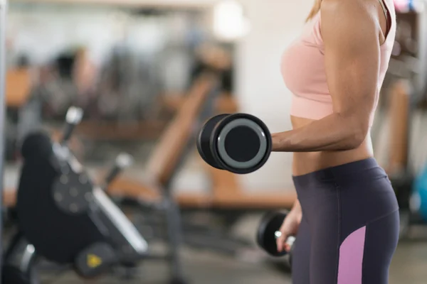 Kvinna som tränar med vikter i gymmet — Stockfoto