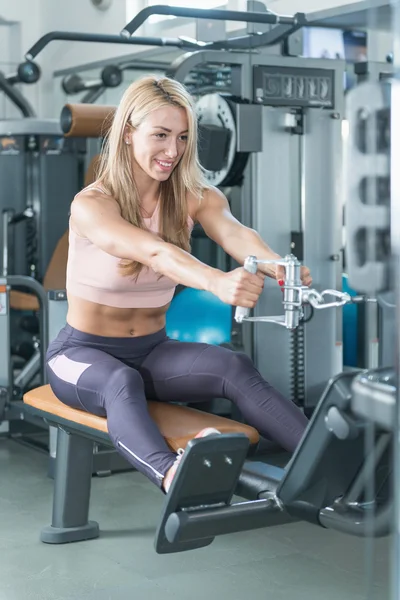 Kobieta, ćwiczenia na maszyny do wiosłowania w siłowni — Zdjęcie stockowe