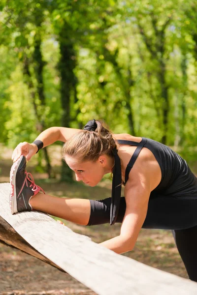 Donna che si estende su una barriera di legno — Foto Stock