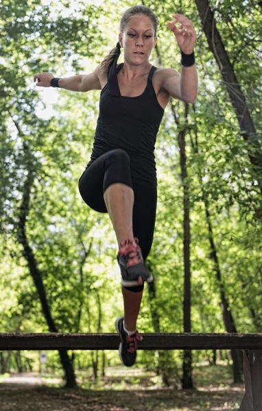 Female athlete crossing wooden barriers — Stock Photo, Image