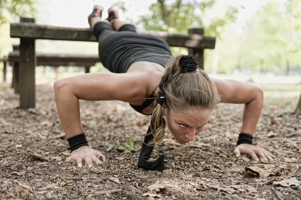 Atleta haciendo flexiones en la barrera del sendero — Foto de Stock