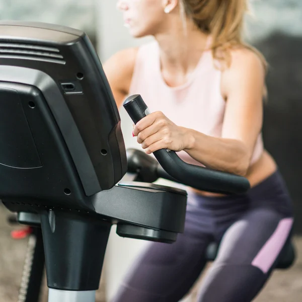 Mujer rubia usando bicicleta de gimnasio —  Fotos de Stock