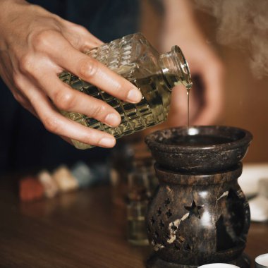 Ayurveda aromaterapi masajı, kadın elinin gerekli yağ dağıtıcısına aromatik yağ dökmesi.