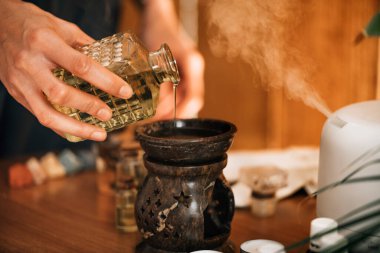 Ayurveda aromaterapi masajı, kadın elinin gerekli yağ dağıtıcısına aromatik yağ dökmesi.