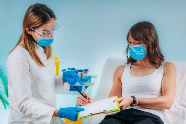 Koruyucu Maskeli Hemşire Bilgi Formu dolduruyor. Covid19 Coronavirüs Krizi sırasında Kan Alma ve Analizi