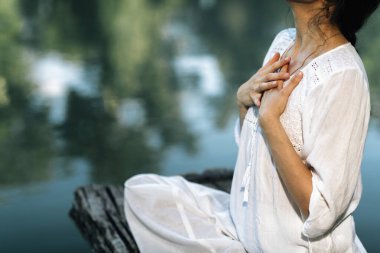 Yoga İnzivası. Nilüfer pozisyonunda oturan ve gölün kenarında meditasyon yapan huzurlu genç bir kadın.
