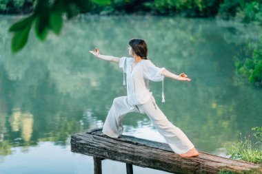 Göl kenarındaki yoga - Savaşçı 2 Poz Çalışan genç kadın veya Virabhadrasana II
