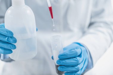 Tarım ürünlerindeki böcek ilaçlarının varlığı için bitki örneklerinin analiz edilmesi. Laboratuvarda çözünmüş örneklerle Test Tüpü 'ne su dökülüyor