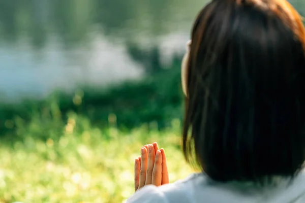 感謝の気持ち瞑想水のそばに座り祈りの場で手を合わせる — ストック写真