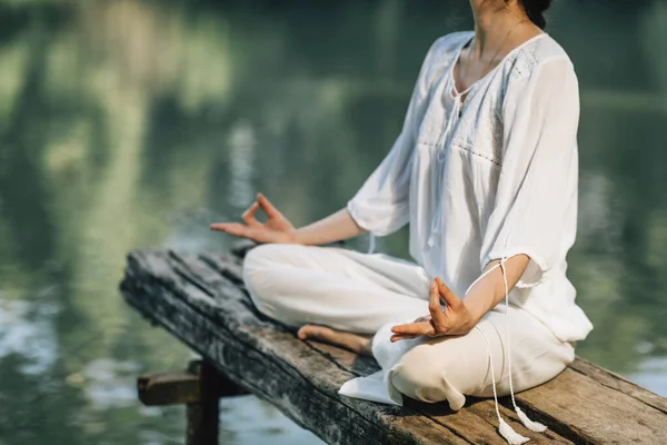 ヨガリトリート 蓮の位置に座って湖のそばで瞑想する平和な若い女性 — ストック写真