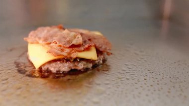 Şef bir burger hazırlar. Sığır eti, domuz, salatalık, sos ve soğan.. 