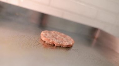 Şef bir burger hazırlar. Sığır eti, domuz, salatalık, sos ve soğan.. 