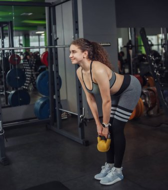 Spor salonunda kettlebell ile egzersiz yapan atletik formda genç bir kadın. Serbest ağırlık, fonksiyonel eğitim