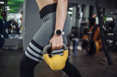 Genç, formda bir kadın spor salonunda kettlebell egzersizi yapıyor. Serbest ağırlık, fonksiyonel eğitim