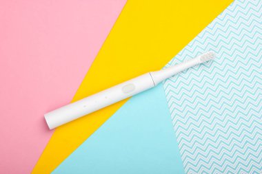 Renkli pastel arka planda elektrikli diş fırçası. Ağız bakımı. Üst görünüm