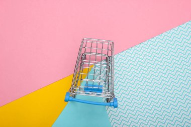 Renkli pastel arka planda mini alışveriş arabası. Üst Manzara. Minimalizm alışveriş kavramı