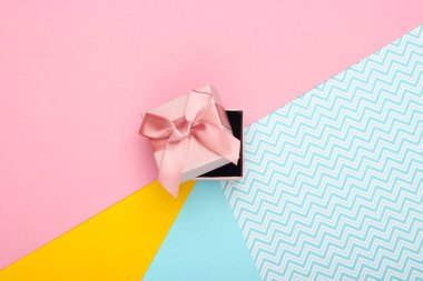 Renkli arka planda fiyonklu bir hediye kutusu. Pastel renk eğilimi. Üst görünüm