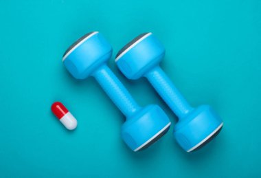 Sporda farmakoloji. Mavi arka planda aptal ve kapsül. Vitaminler, steroitler. Üst görünüm