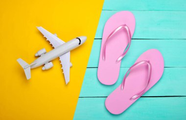 Terlikler ve uçak sarı, mavi ahşap arka planda. Üst Manzara. Plaj Tatili Konsepti, Seyahat