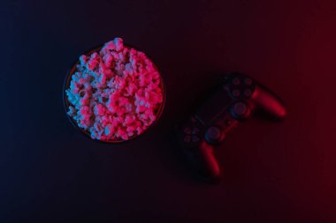 Av köpekleri ve bir kase patlamış mısır. Neon pembe ışık. Oyun, eğlence ve eğlence konsepti. Üst görünüm