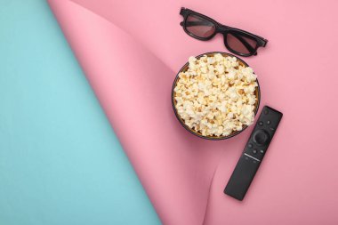 Bir kase patlamış mısır, 3D gözlükler, mavi pembe arka planda uzaktan kumanda. Boş zaman ve eğlence konsepti. Üst görünüm