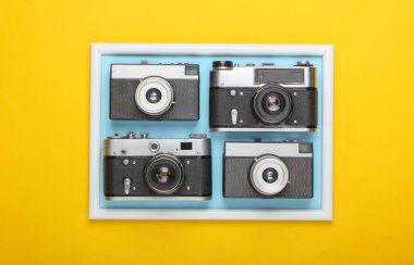 Sarı arkaplanda fotoğraf çerçeveli birçok Retro kamera var. Stüdyo çekimi. Yaratıcı düz yatak. Üst Manzara. Minimalizm