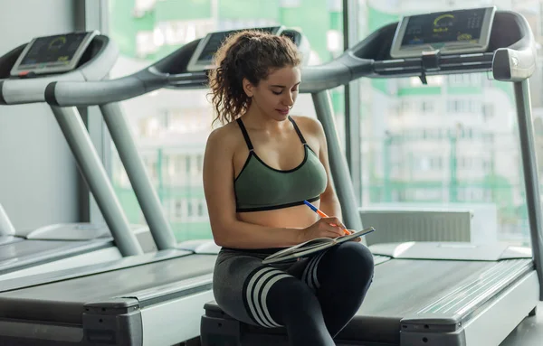 Een Jonge Fitte Vrouw Schrijft Informatie Een Trainingsboek Voor Verdere — Stockfoto