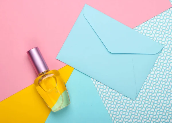 Envelope with romantic letter and perfume bottle on a pastel background. Top view