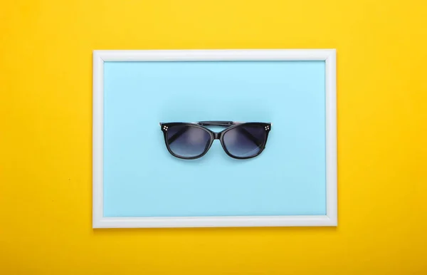 Okulary Przeciwsłoneczne Żółtym Tle Ramką Zdjęcia Studyjne Kreatywne Płaskie Łóżko — Zdjęcie stockowe