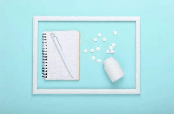 Tabletki Notatnik Niebieskim Tle Białą Ramką Zdjęcia Studyjne Kreatywna Medycyna — Zdjęcie stockowe