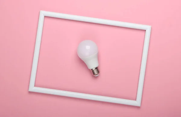LED light bulb on pink background with white frame. Studio shot. Creative flat lay. Top view. Minimalism