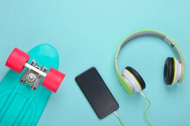 Düz bir hipster kompozisyonu vardı. Mavi pastel arka planda akıllı telefonlu kruvazör ve stereo kulaklıklar. Yaz eğlencesi. Üst görünüm
