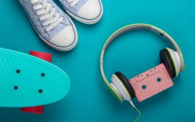 Düz yerde hipster şeyler yatıyordu. Kruvazör tahtasındaki spor ayakkabıları, mavi arka planda ses kaseti olan stereo kulaklıklar. Retro 80 'lerin eğlenceleri. Üst görünüm