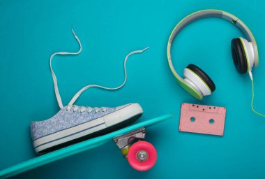 Hipster ergen şeyleri. Retro stil düz yatıyordu. Kaykay, spor ayakkabı, kulaklık ve mavi arka planda diğer aksesuarlar. Eğlence ve rahatlama. Sümer eğlencesi