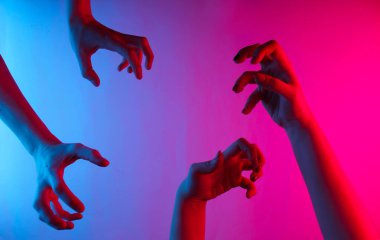 Cadılar Bayramı konsepti Korkunç jestleri olan kadın elleri. Neon mavi-pembe eğimli ışık. Gece parıltısı. Yaratıcı sanat
