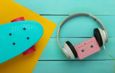 Düz bir hipster kompozisyonu vardı. Kruvazör tahtası, ses kaseti, mavi ahşap arka planda kulaklık. Retro 80 'lerin eğlenceleri. Yaz eğlencesi. Üst görünüm