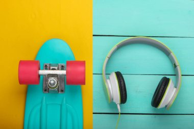 Sarı arka planda kruvazör tahtası ve stereo kulaklıklar. Ergenlik sorunları. Yaz eğlencesi. Üst görünüm