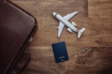 Seyahat konsepti. Eski valizler, uçak figürleri, ahşap zeminde pasaport. Uçuş yolculuğu, yolculuk, yolculuk. Düz kompozisyon. Üst görünüm
