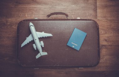 Seyahat konsepti. Eski valizler, uçak figürleri, ahşap zeminde pasaport. Uçuş yolculuğu, yolculuk, yolculuk. Düz kompozisyon. Üst görünüm