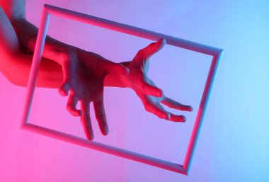 Yaratıcı sanat. Süzülen bir çerçeveden süzülen kadın elleri ve neon holografik ışık. Kıvılcım. Pop sanat. 80 'ler