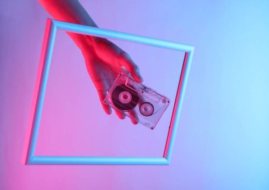 Yaratıcı sanat. Kadın el, süzülen bir çerçeveden süzülen bir holografik ışıkla ses kasetini tutuyor. Kıvılcım.