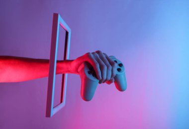 Yaratıcı sanat. Kadın el, neon holografik ışıkla yükselen bir çerçevede retro oyun sahasını tutuyor. Kıvılcım. 80 'lerin eğlencesi